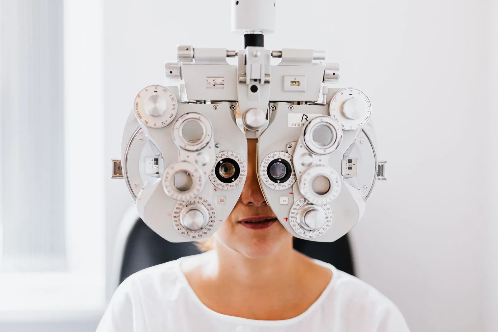 Pacientă la examenul optometric, privind prin foropter