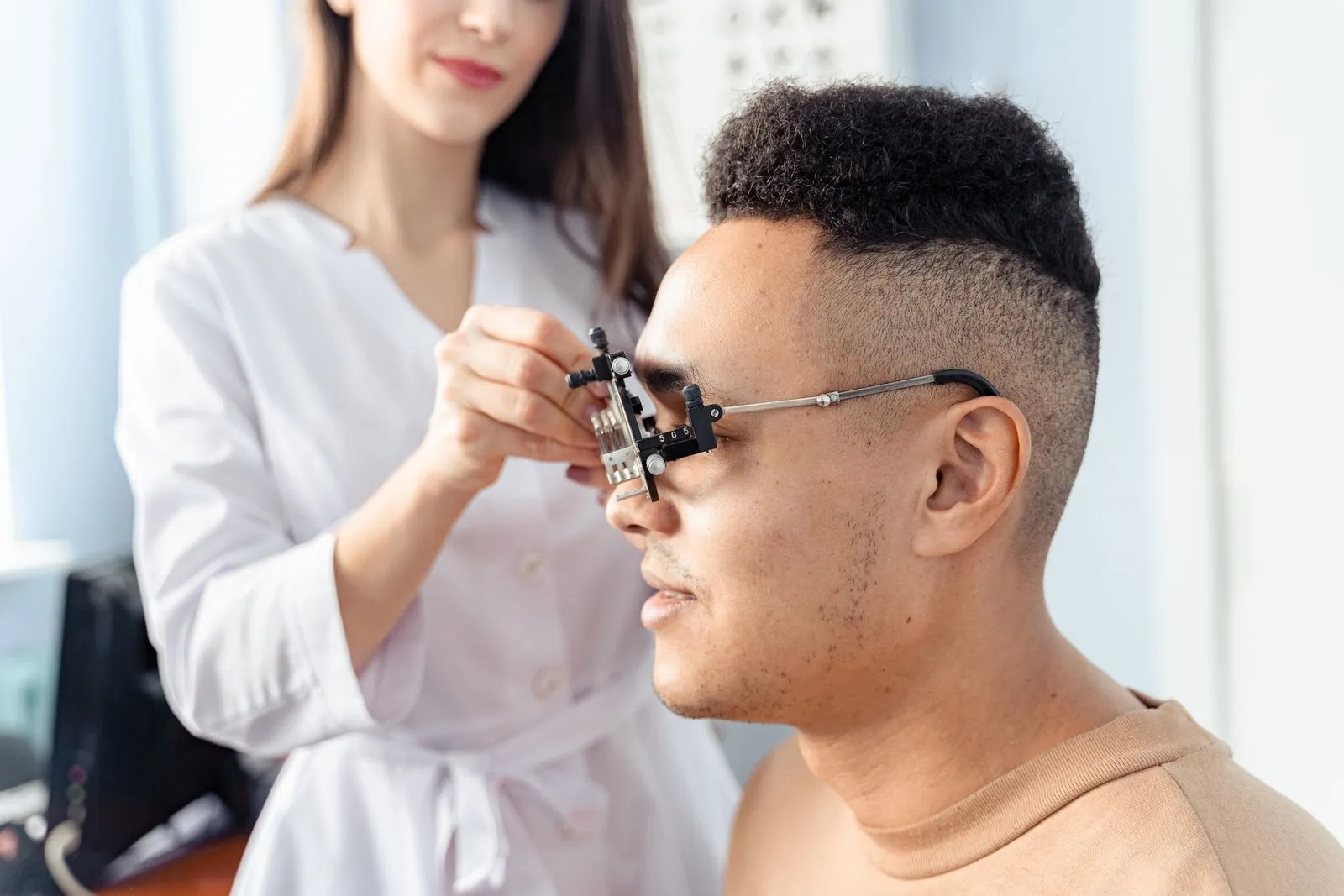 Optometristă care potrivește o ramă de probă pe fața unui pacient