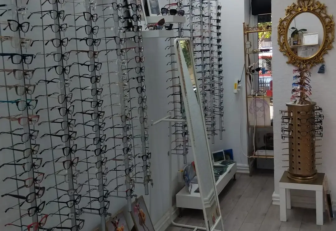 Peretele cu rame de ochelari și oglinda aurie din magazinul L’optique Monique de pe Bd. Chișinău